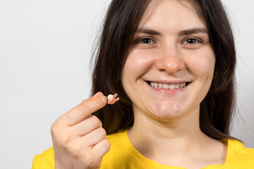 A female patient of a dental clinic holds in her hand a single potes - a removable tooth as an...