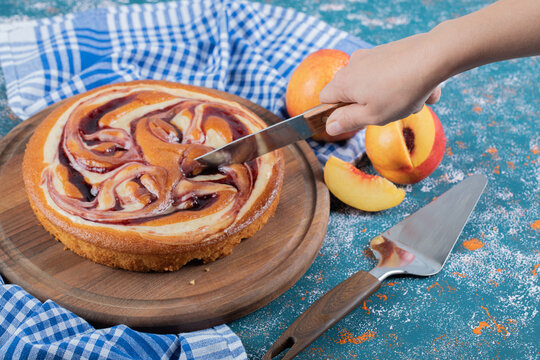 Cutting a slice of strawberry cake on a wooden baord
