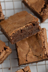 Pieces of freshly baked brownies in a square form on a cooling tray. Flat lay composition with tasty, sweet brownies isolated on white background. Close-up of a chocolate pie. Dessert menu concept.