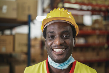 African worker man smiling on camera inside warehouse during coronavirus outbreak - Focus on mouth