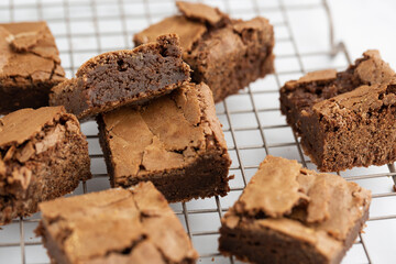 Pieces of freshly baked brownies in a square form on a cooling tray. Flat lay composition with...