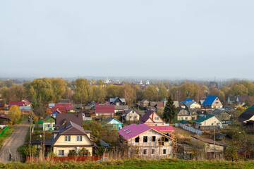 spring village landscape, top view of the street of the Russian village, roofs are visible, buildings among the trees and a blue sky