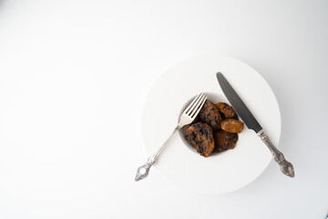 Chaga, birch tree mushroom in white plate with silver knife and fork on grey background. Natural medicine, antioxidant, superfood.