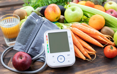 Blood pressure monitor and fresh fruits with vegetables against wooden table. Healthy lifestyle and...