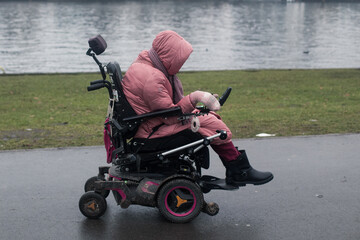Woman wearing warm clothes riding at the wheelchair