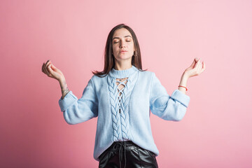 Brunette girl in the studio on a pink background shows hands gesture zen mudra