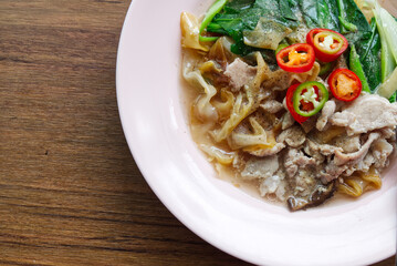 Fried Wide Rice Noodles with Pig in Gravy Sauce on the Wood Table.