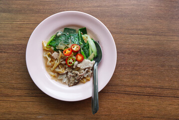 Fried Wide Rice Noodles with Pig in Gravy Sauce on the Wood Table.