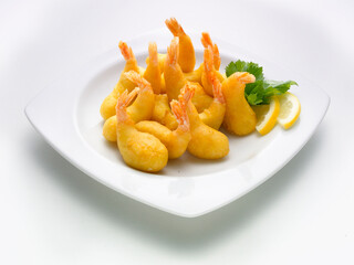 gambas rebozadas y fritas. Con limón sobre fondo blanco. battered and fried prawns. With lemon on white background.