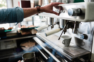 unrecognizable person preparing coffee in cafeteria