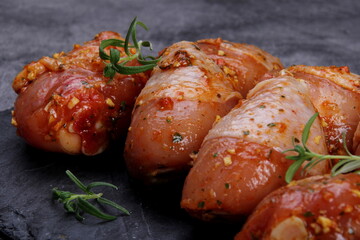 Marinated raw chicken legs on black stone plate. Uncooked marinated chicken