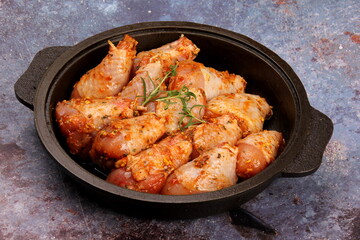 Marinated raw chicken legs on black pan. Uncooked marinated chicken. Marinated chicken drumsticks