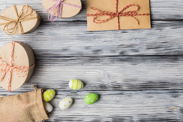 Oval gift boxes, envelope and painted eggs on old wooden background with copy space. Easter greeting concept