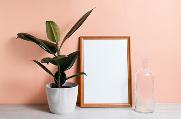 Poster with copy space. Bookshelf with Home plant ficus, poster, and vase in a Scandinavian-style interior. Pastel beige wall, minimalism.