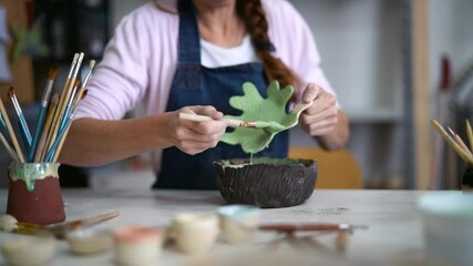 Woman potter painting clay figure in workshop - Artisan work and creative craft concept