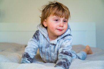 Fototapeta premium Little toddler waking up in the morning, lying in bed. Sleepy child at home.