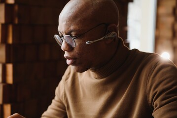 Focused african man wearing headphones watching webinar training making notes study online learning language on computer, black male student looking at laptop elearning in internet write information