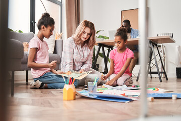 Obraz premium Caucasian woman watching how her multiracial daughters creating pictures