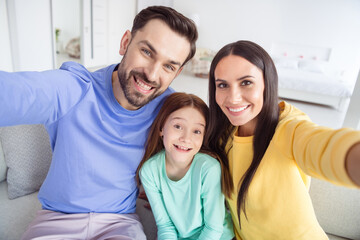 Fototapeta premium Photo of cheerful family mom dad daughter happy positive smile make selfie record video sit sofa home