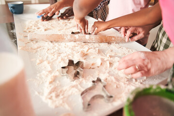 Woman wearing apron preparing cookies with her multiracial family