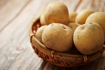 Fototapeta na wymiar Fresh raw potatoes on a wooden background