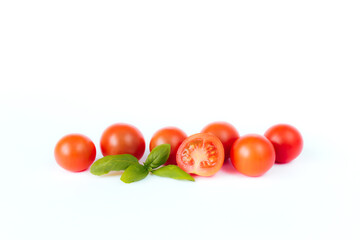Red cherry tomatoes with green basil on a white background