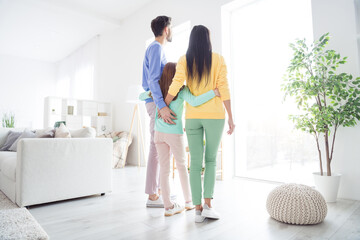 Full body rear view photo of family hug cuddle embrace look watch window enjoy time together indoors