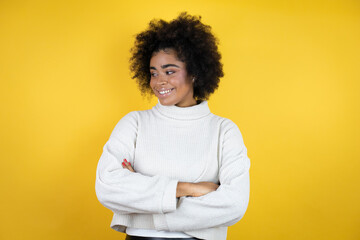 Obraz na płótnie Canvas African american woman wearing casual sweater over yellow background looking to side, relax profile pose with natural face and confident smile.