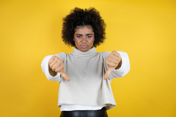 African american woman wearing casual sweater over yellow background with angry face, negative sign...