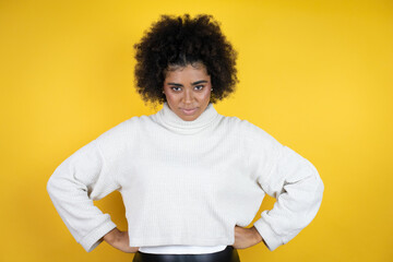 African american woman wearing casual sweater over yellow background skeptic and nervous,...