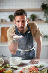 Fototapeta na wymiar Handsome man preparing bread at home. Happy man having fun while baking a fresh pasta.