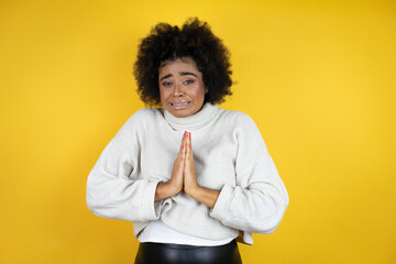 African american woman wearing casual sweater over yellow background begging and praying with hands together with hope expression on face very emotional and worried