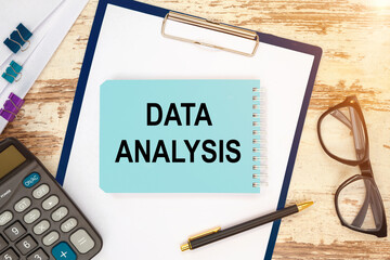 Notebook with text - Data Analysis near office supplies.