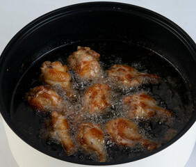 Closeup of frying chicken in electric pot