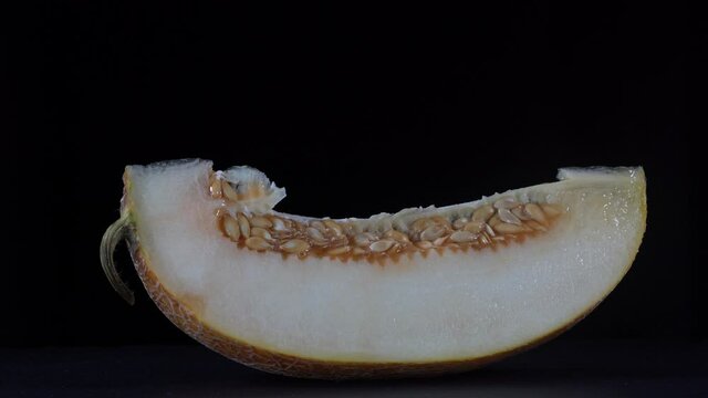 Yellow melon on a black background, close up. Rotates slice yellow melon, macro