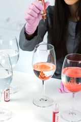 The girl is dripping pigments into glasses. Dissolving the pigment in water. Tube with the inscription: Pigments, Lips.