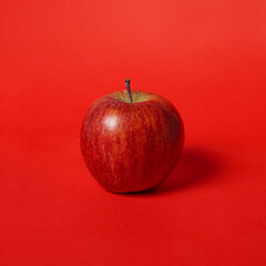 Red apple isolated on red background. Apples contain vitamin C. Apples, including fruit that is rich in fiber. The similarity of fruit color and background adds an elegant impression to the image.