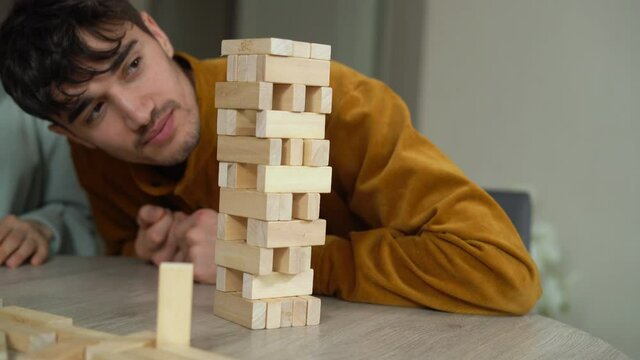 a man and a woman are playing Jenga. Educational board games for the whole family. a dice house. The family has fun playing with wooden cubes.