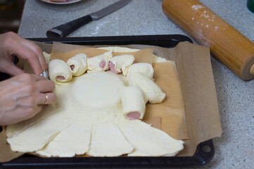 Fototapeta na wymiar Cooking sausages in dough with cheese at home in the kitchen for children.