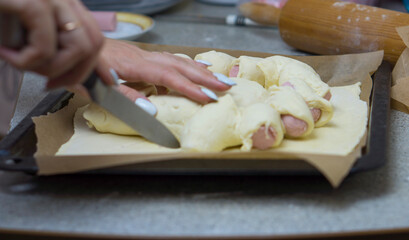 Cooking sausages in dough with cheese at home in the kitchen for children.