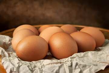 Brown eggs on a dark background. Raw brown chicken eggs on crumpled wrapping paper. High calorie protein food concept.