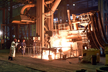 Naklejka na ściany i meble Workers in protective equipment in a foundry during the production of steel components - workplace industrial factory