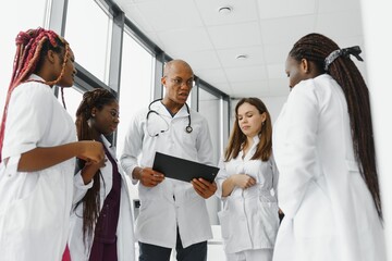 Afro-American doctor leading his team with folded arms and looking at the camera