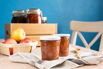 Homemade apple jam marmalade with cloves and cinnamon from organic apples in a transparent glass near wooden spoon. Homemade autumn jam confiture preserves.