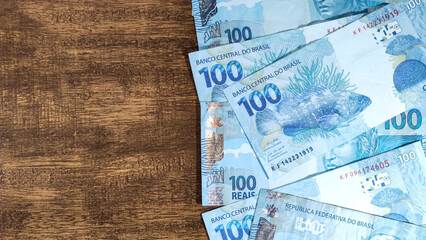 various money notes of 100 reais from brazil on a wood background. space for text. money from brazil. earn money. Real, Currency, Money, Dinheiro, Reais, Brasil.