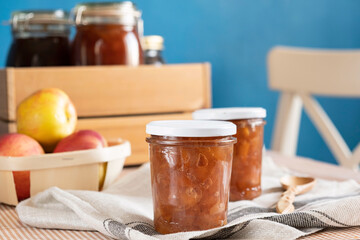 Homemade apple jam marmalade with cloves and cinnamon from organic apples in a transparent glass near wooden spoon. Homemade autumn jam confiture preserves.