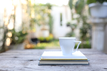 white ceramic cup and notebooks on wooden table