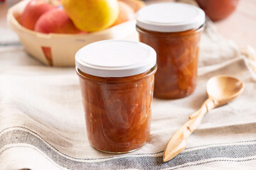 Homemade apple jam marmalade with cloves and cinnamon from organic apples in a transparent glass near wooden spoon. Homemade autumn jam confiture preserves.