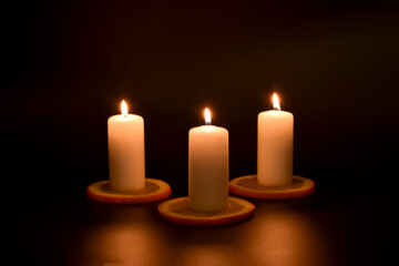 Białe, palące się świeczki i plasterki pomarańczy.