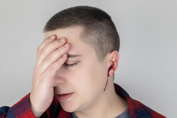 Fototapeta premium A man whose ear is bleeding. Vascular rupture, damage to the tympanic membrane, ear diseases, oncology, otitis media, myringitis